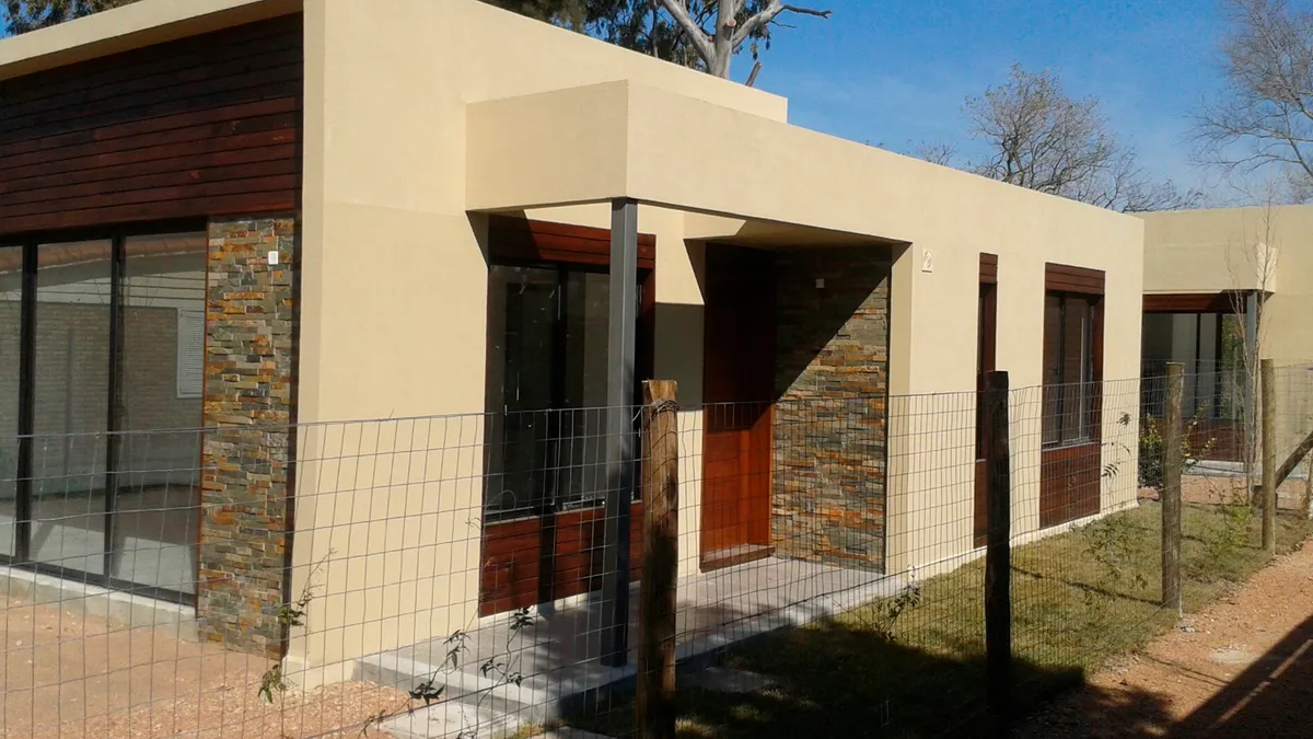 Vista oblicua de una vivienda en Solymar y del encuentro entre acceso, aberturas y revestimiento.