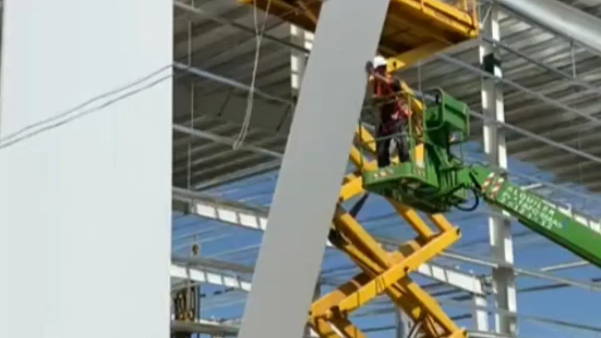 Montaje de paneles junto a la estructura de la nave Bader, con trabajadores sobre plataformas elevadoras.
