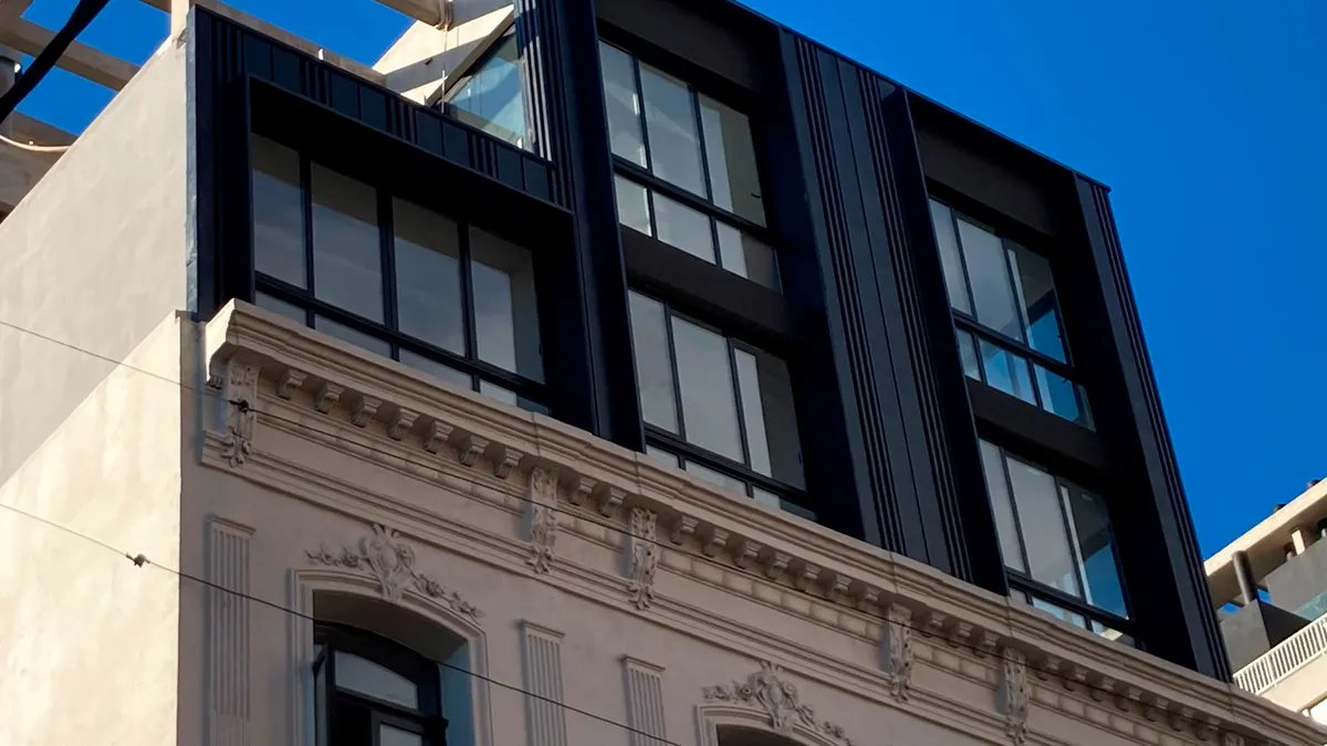 Detalle del revestimiento oscuro de los niveles superiores y su encuentro con la fachada existente del Edificio Maldonado.