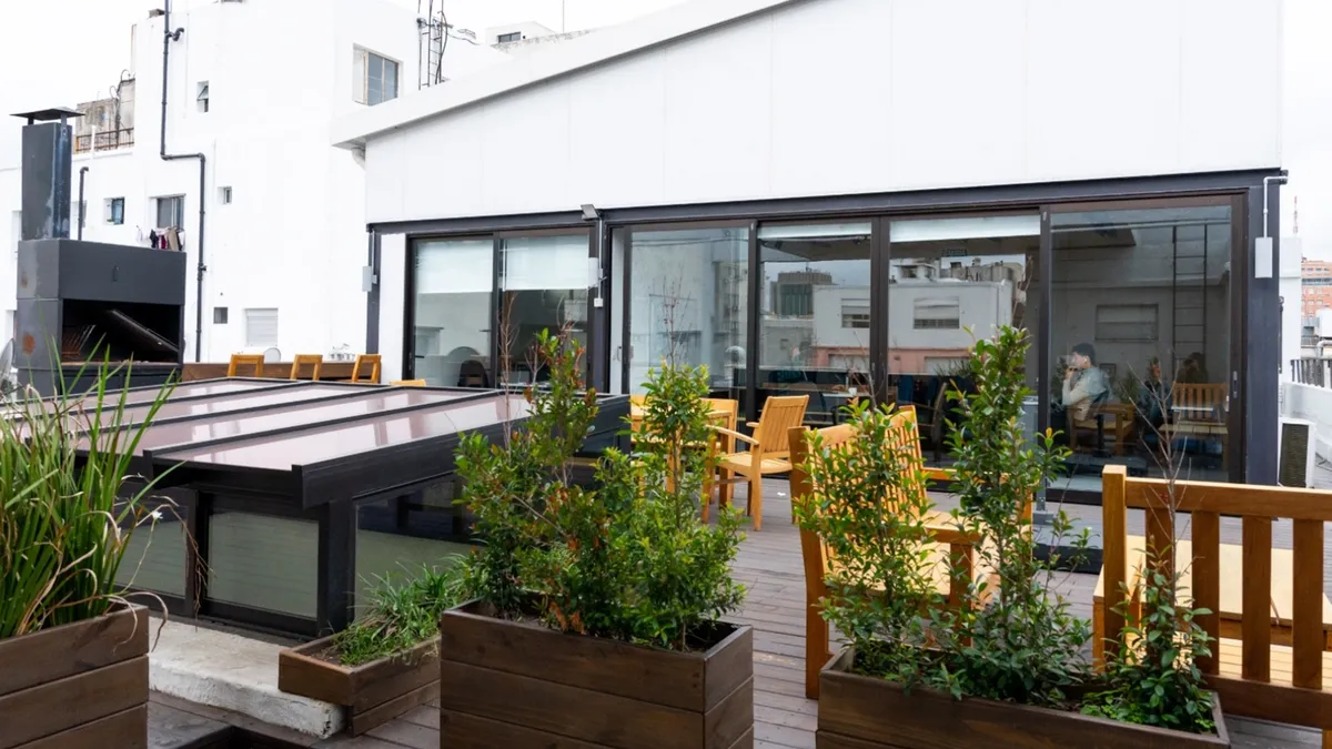 Terraza de Oficinas Piso 7, con jardineras y aberturas vidriadas hacia el interior.