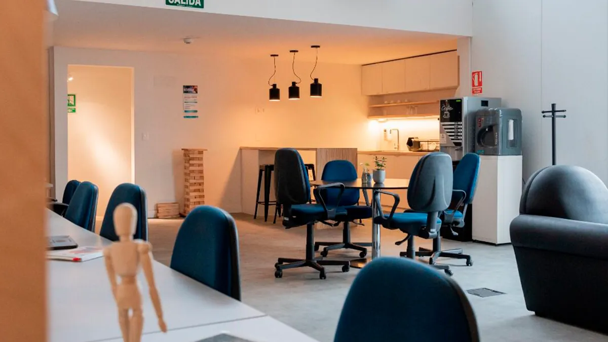 Interior terminado de Oficinas Piso 7, con mesas, sillas y sector de apoyo.