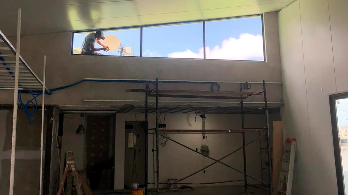Interior de la ampliación de Oficinas Piso 7 durante la ejecución, con andamio y ventana alta.